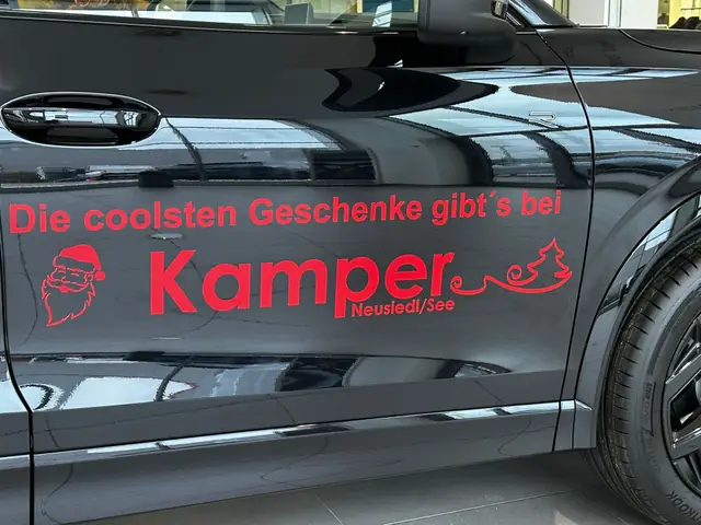 Schwarzes Auto mit rotem, geplottetem Werbeschriftzug an der Fahrertür