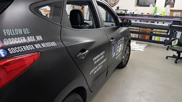 Seitenbeschriftung mit Text und Logo auf einem grauen SUV