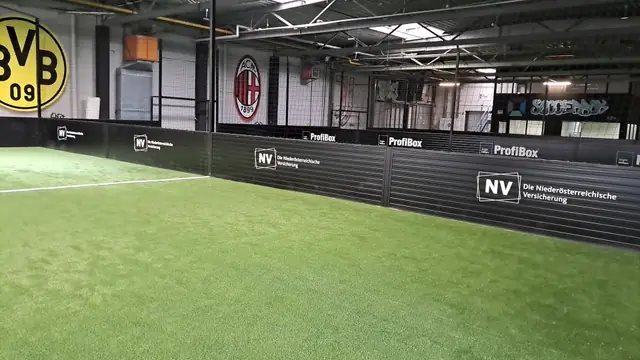 Bandenwerbung mit Sponsorenlogos auf schwarzen Banden in einer Soccerhalle