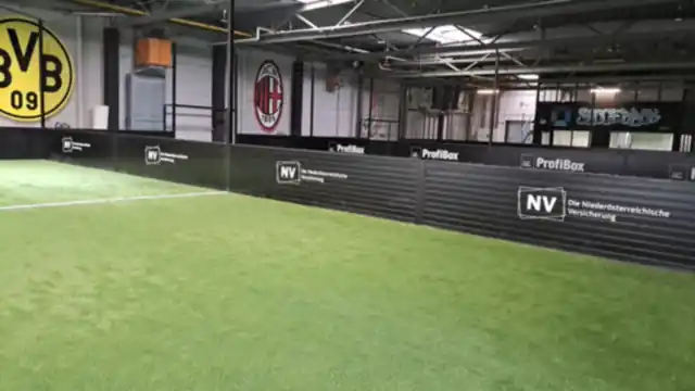 Bandenwerbung mit Sponsorenlogos auf schwarzen Banden in einer Soccerhalle