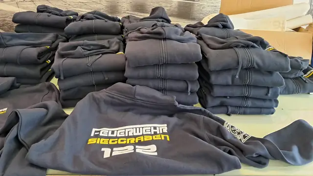 Stapel dunkelblauer Pullover mit Aufdruck der Feuerwehr Sieggraben