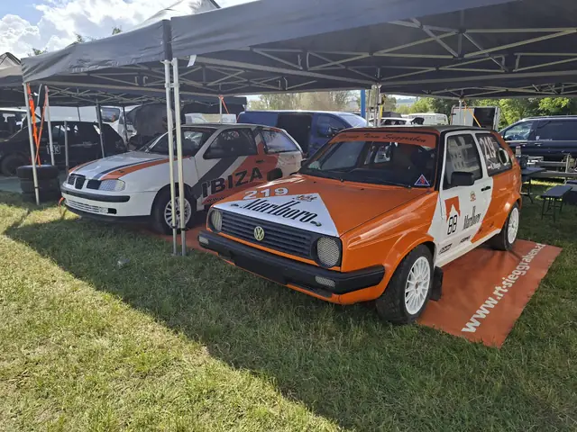 Zwei folierte Rallyeautos im Fahrerlager unter einem Zelt