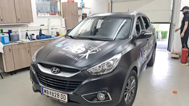 Grauer SUV mit Teilfolierung auf Motorhaube und Kotflügel in der Werkstatt