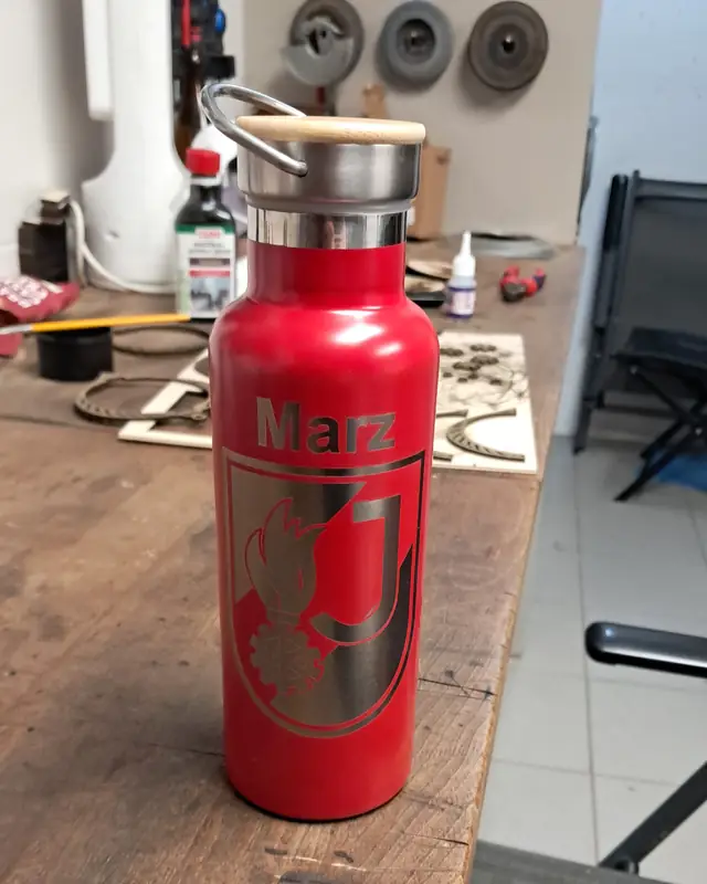 Rote Edelstahl-Trinkflasche mit Lasergravur auf dem Werktisch